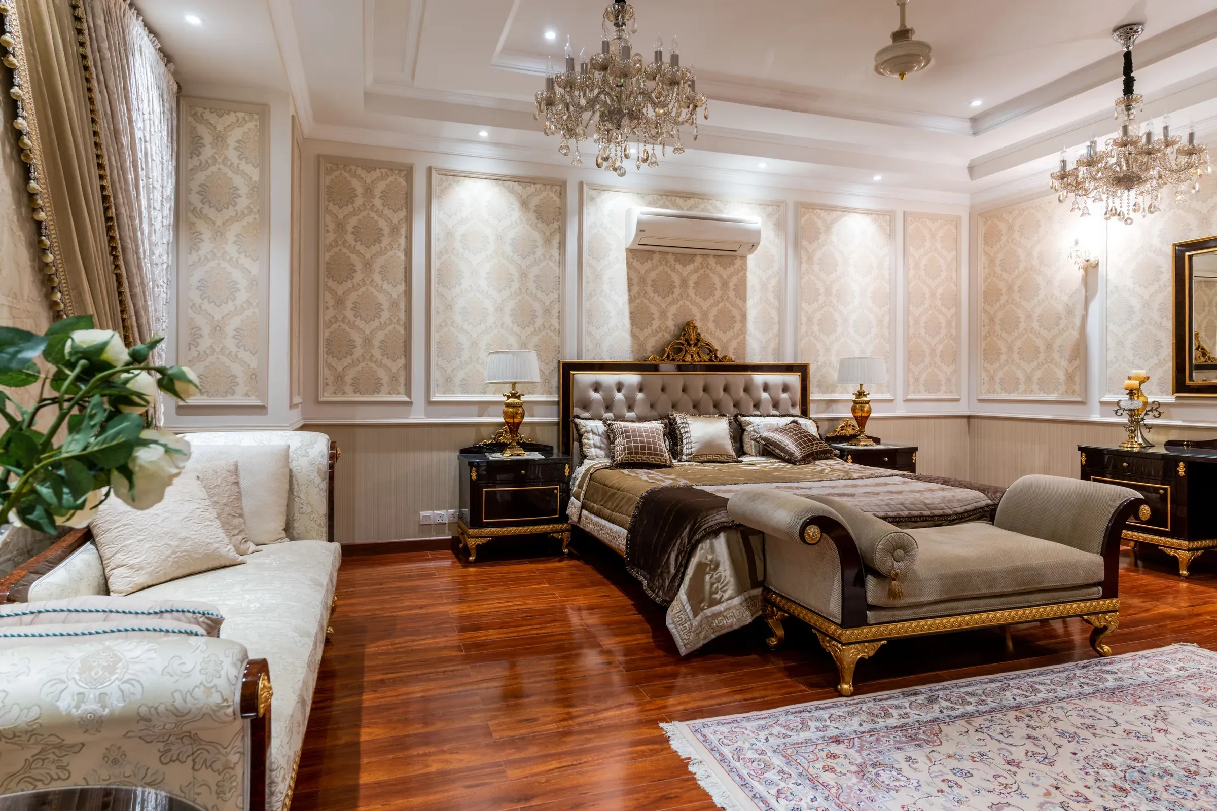 Classic master bedroom with damask wallpaper panels, crystal chandeliers, tufted headboard and wooden floor