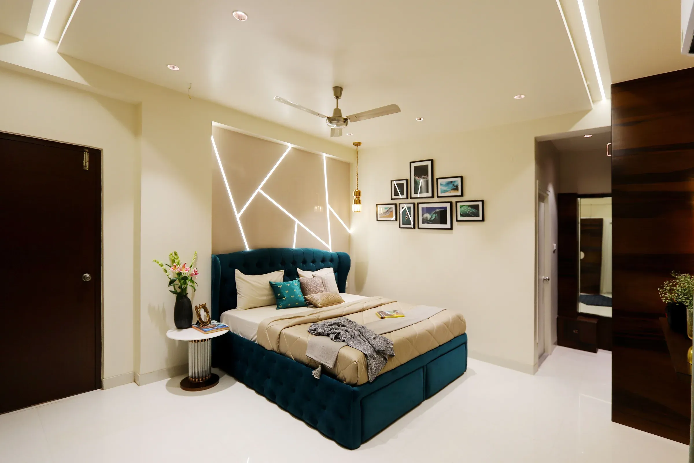 Bedroom with a teal tufted velvet bed, geometric LED lines on the headboard wall and a framed photo gallery