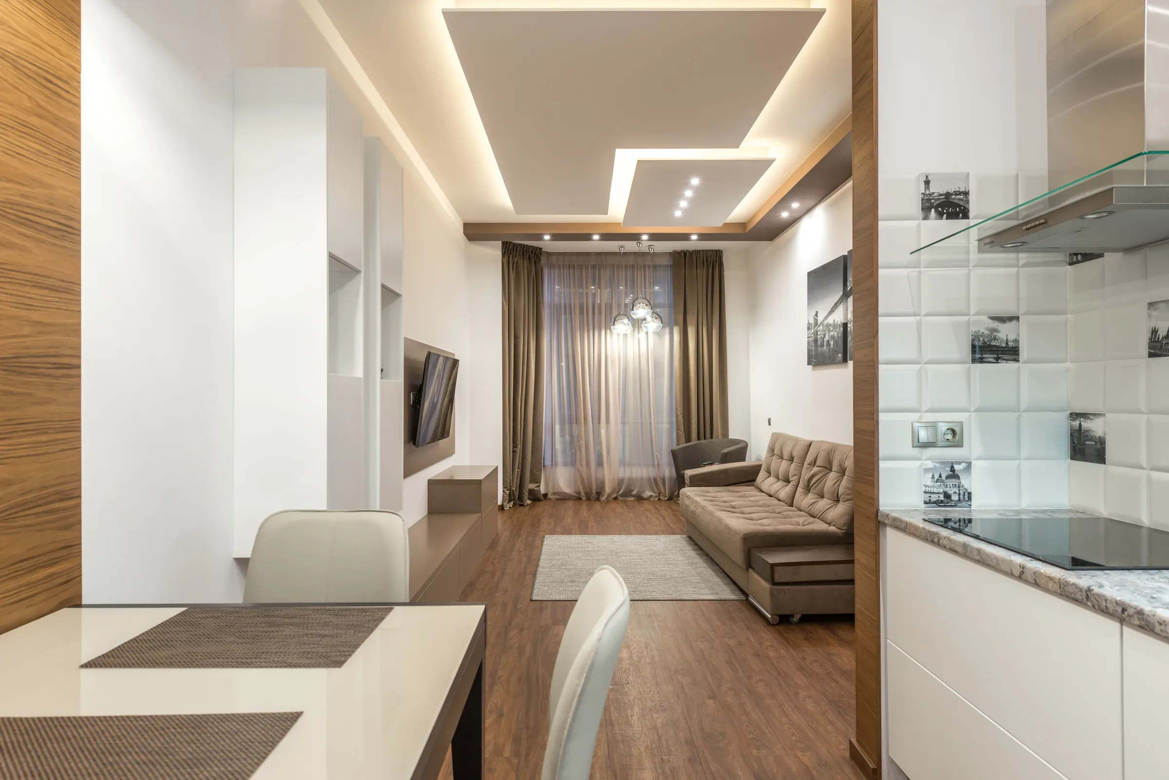 Open-plan living, dining and kitchen under a floating false ceiling panel with cove light and spotlights