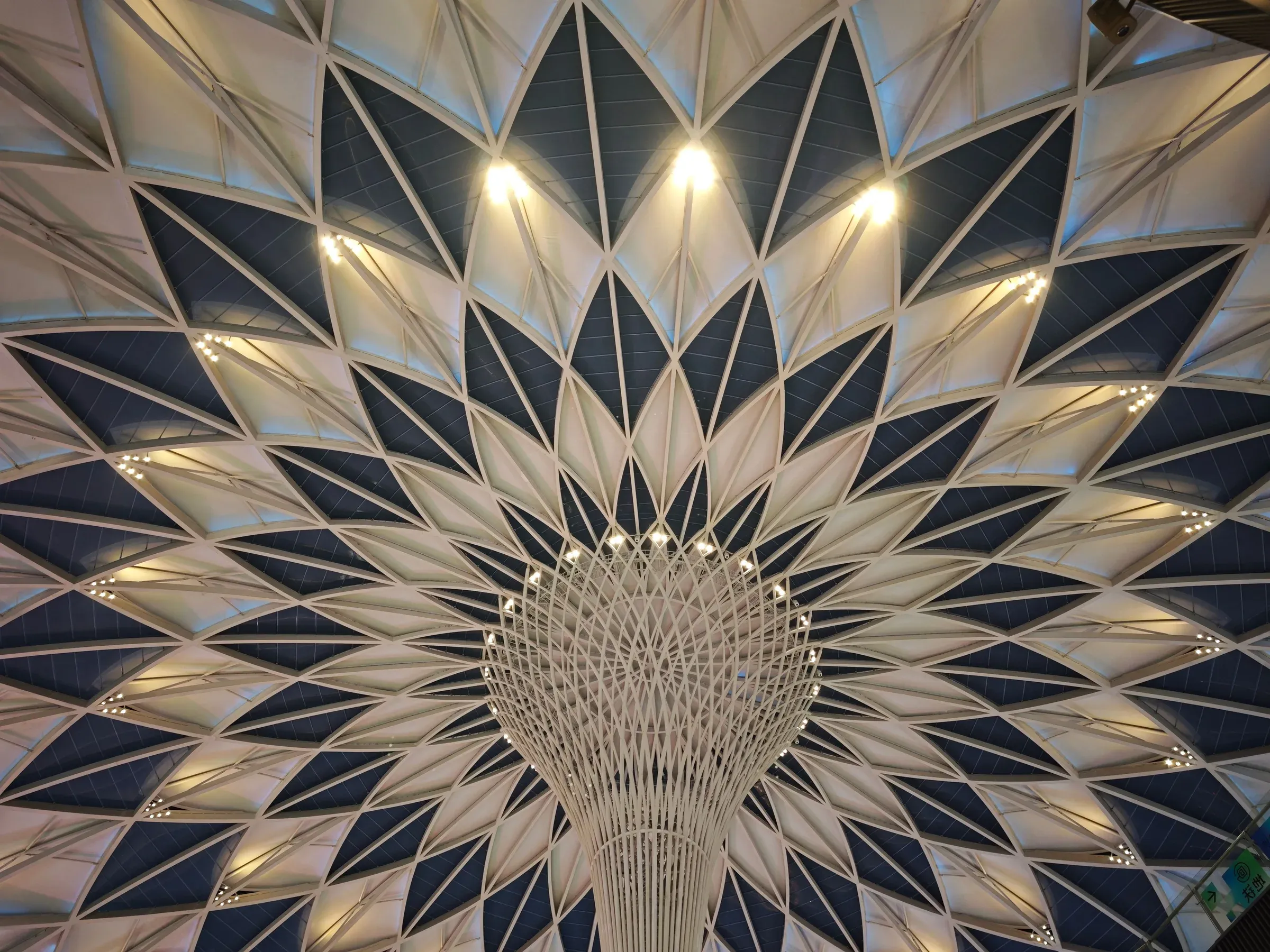 Geometric lotus-pattern ceiling structure with spotlights radiating from a central white column