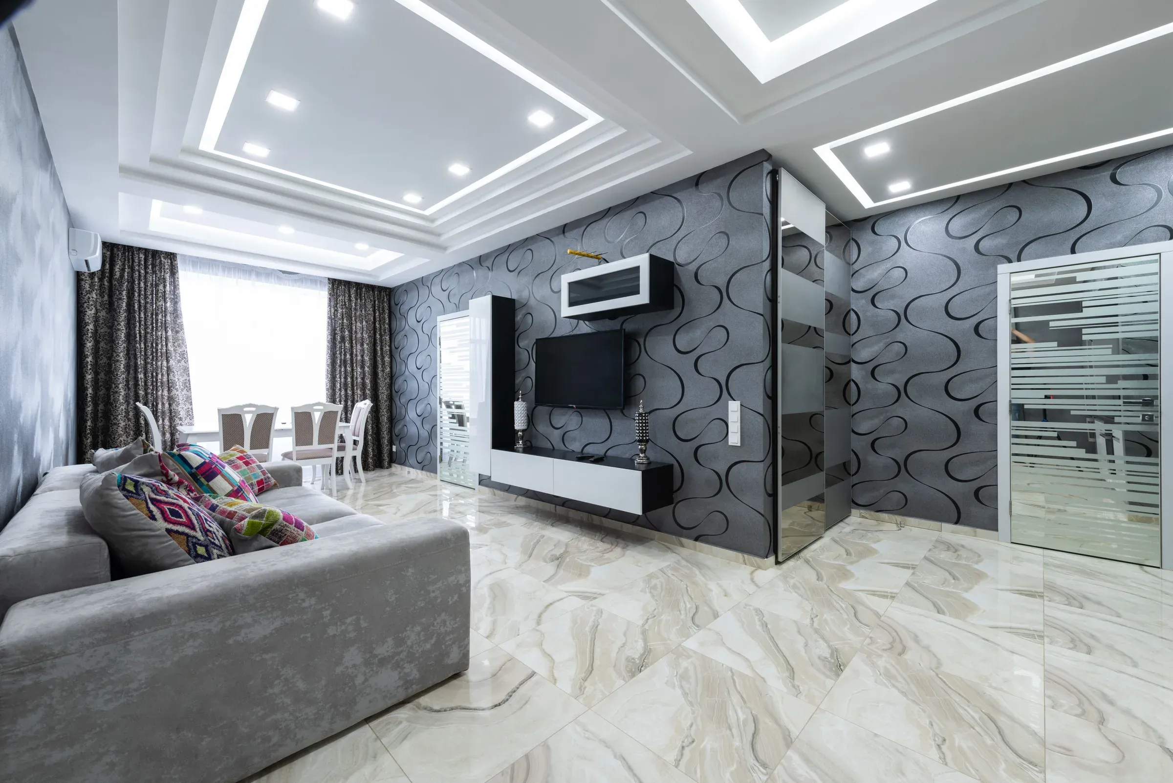 Living room with a layered POP ceiling and spotlights, black swirl wallpaper, floating TV unit and marble floor