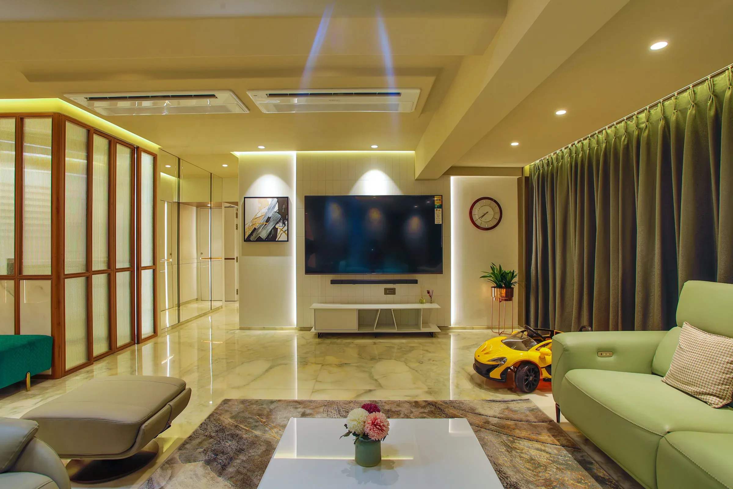 Indian living room with a marble floor, mint leather sofa, backlit TV wall and fluted glass wooden partition