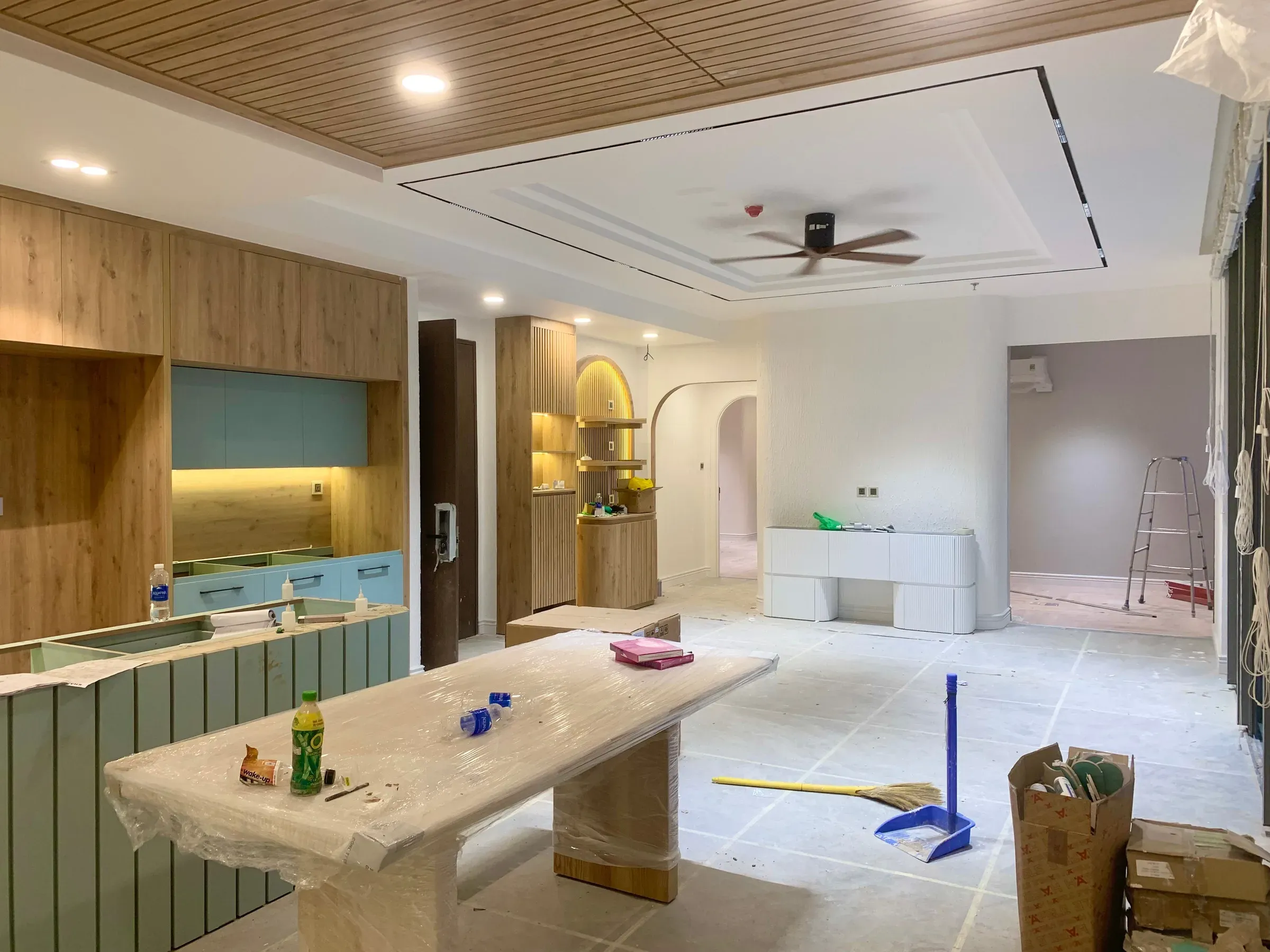 Home renovation in progress: new wooden ceiling slats, covered kitchen island, arched niche and ceiling fan