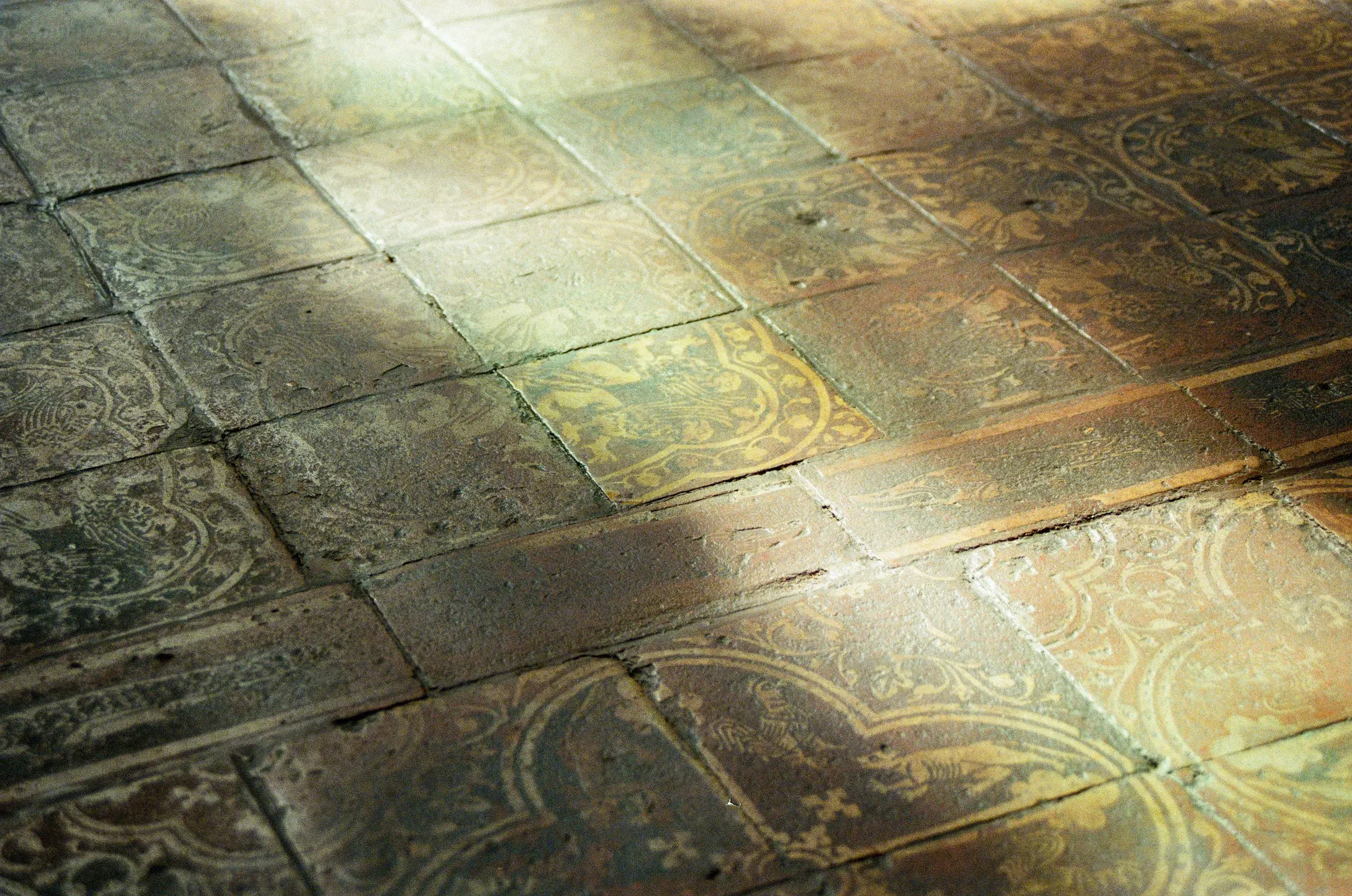Close-up of antique patterned terracotta floor tiles in soft sunlight