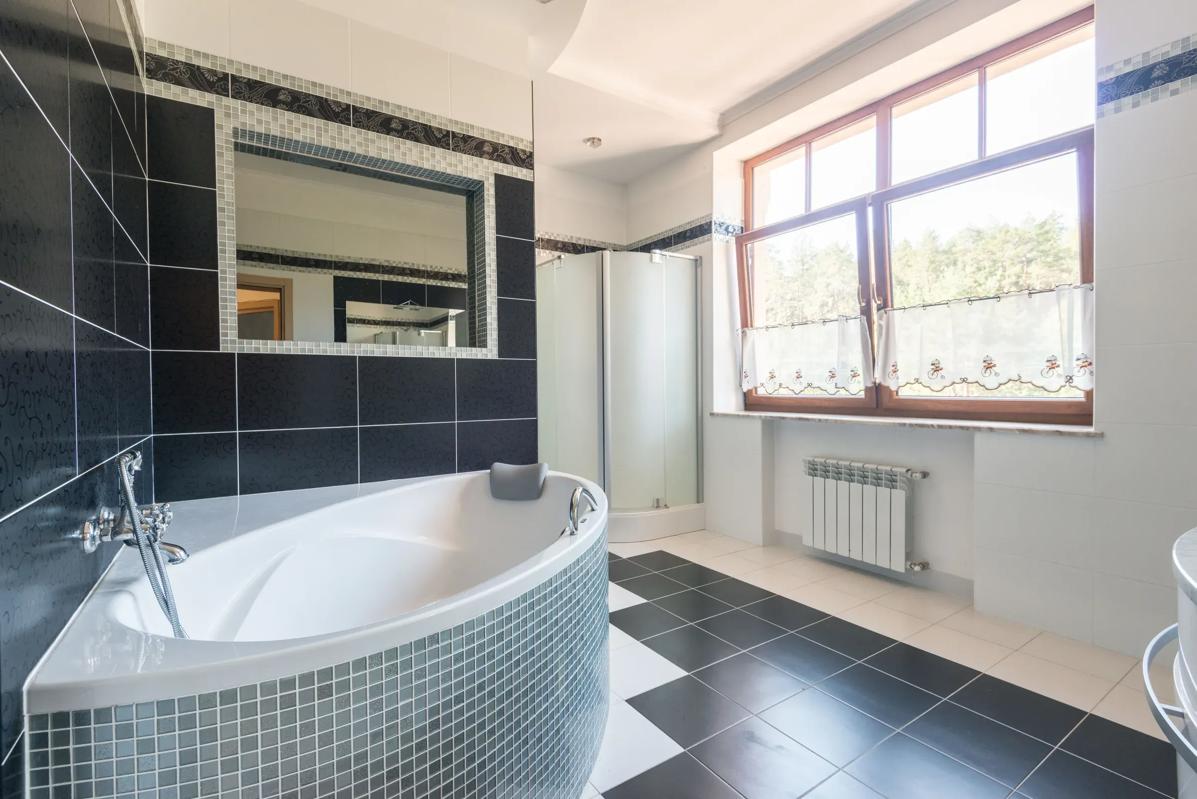 Bathroom with glossy black wall tiles, a black-and-white checkered floor and mosaic-clad corner bathtub