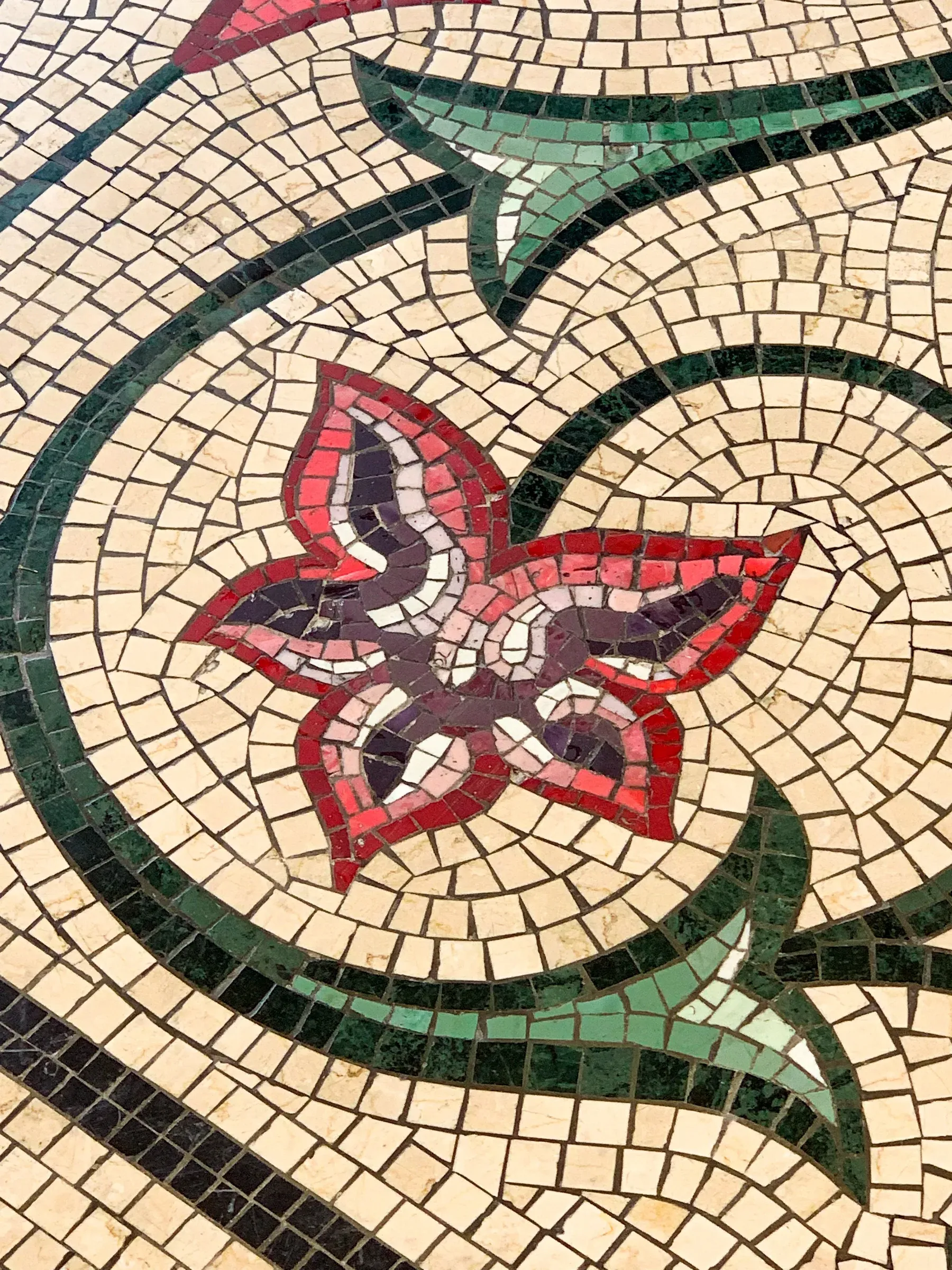 Floral stone mosaic floor with a red flower and green scroll pattern