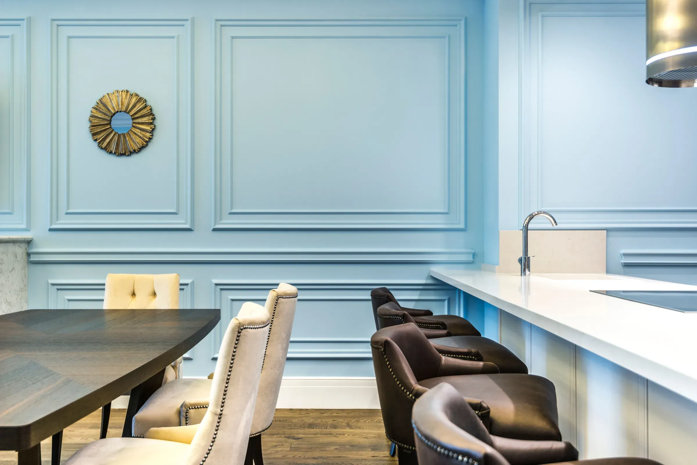 Dining and kitchen bar with sky blue moulded walls, a sunburst mirror and leather bar chairs