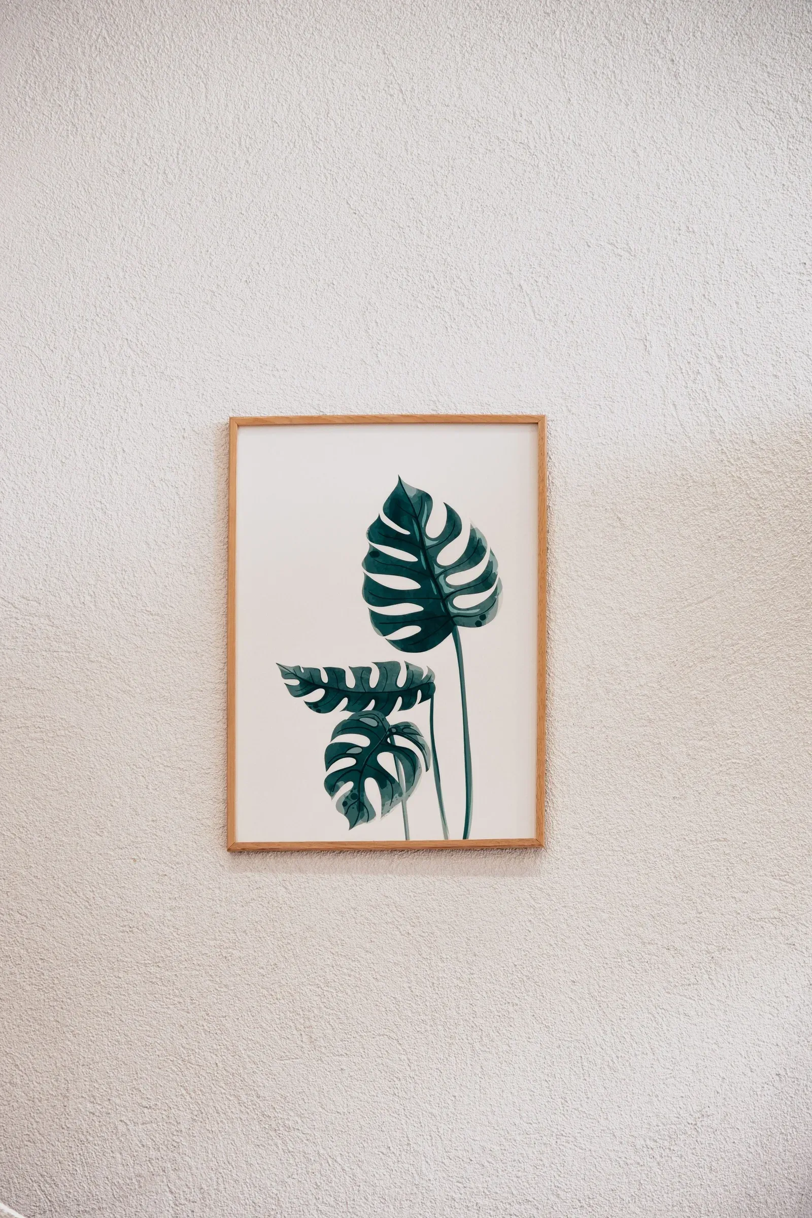 Single framed monstera leaf print on a textured white wall