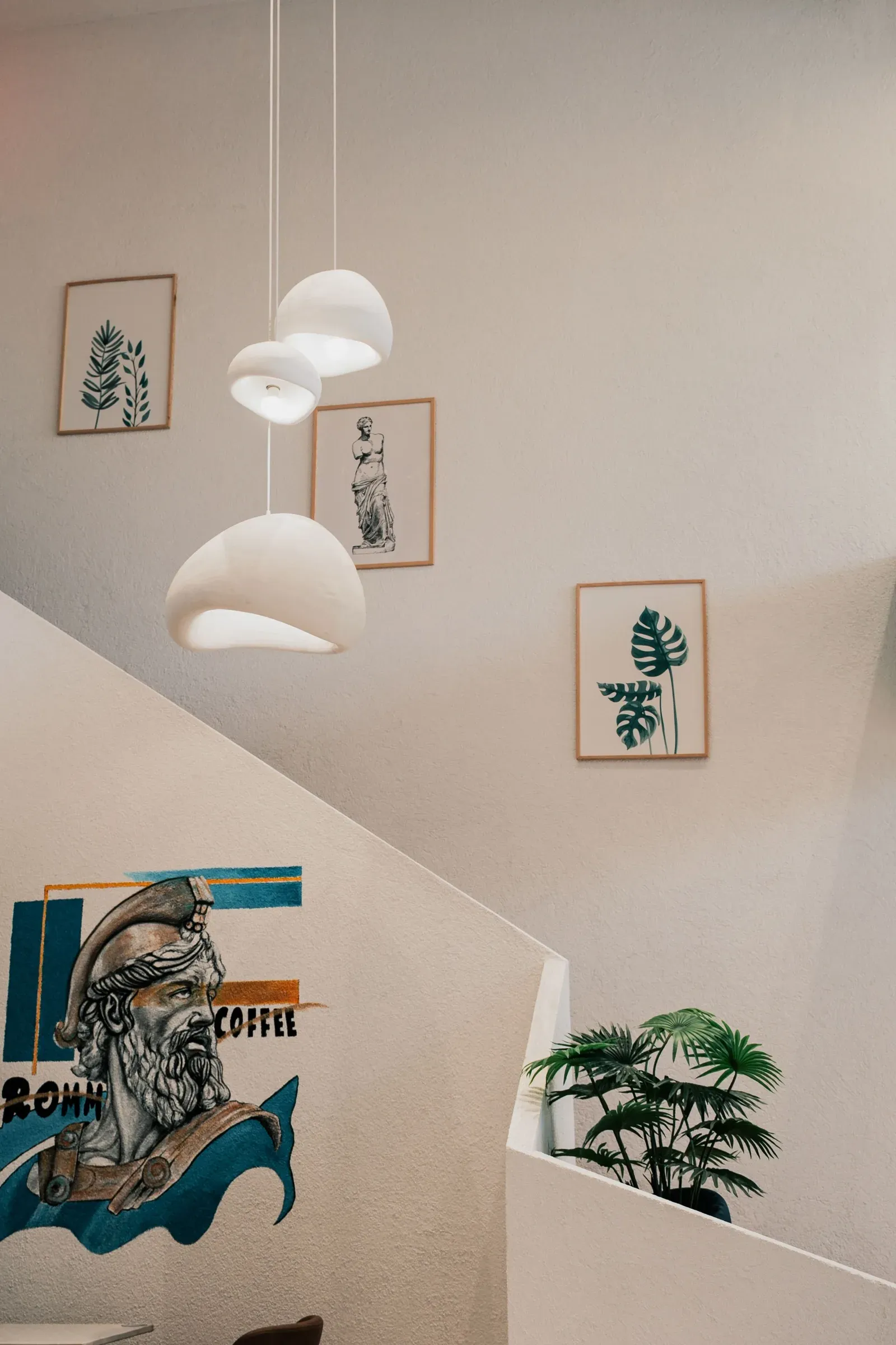 Staircase wall with botanical frames, cloud pendant lights and a painted mural
