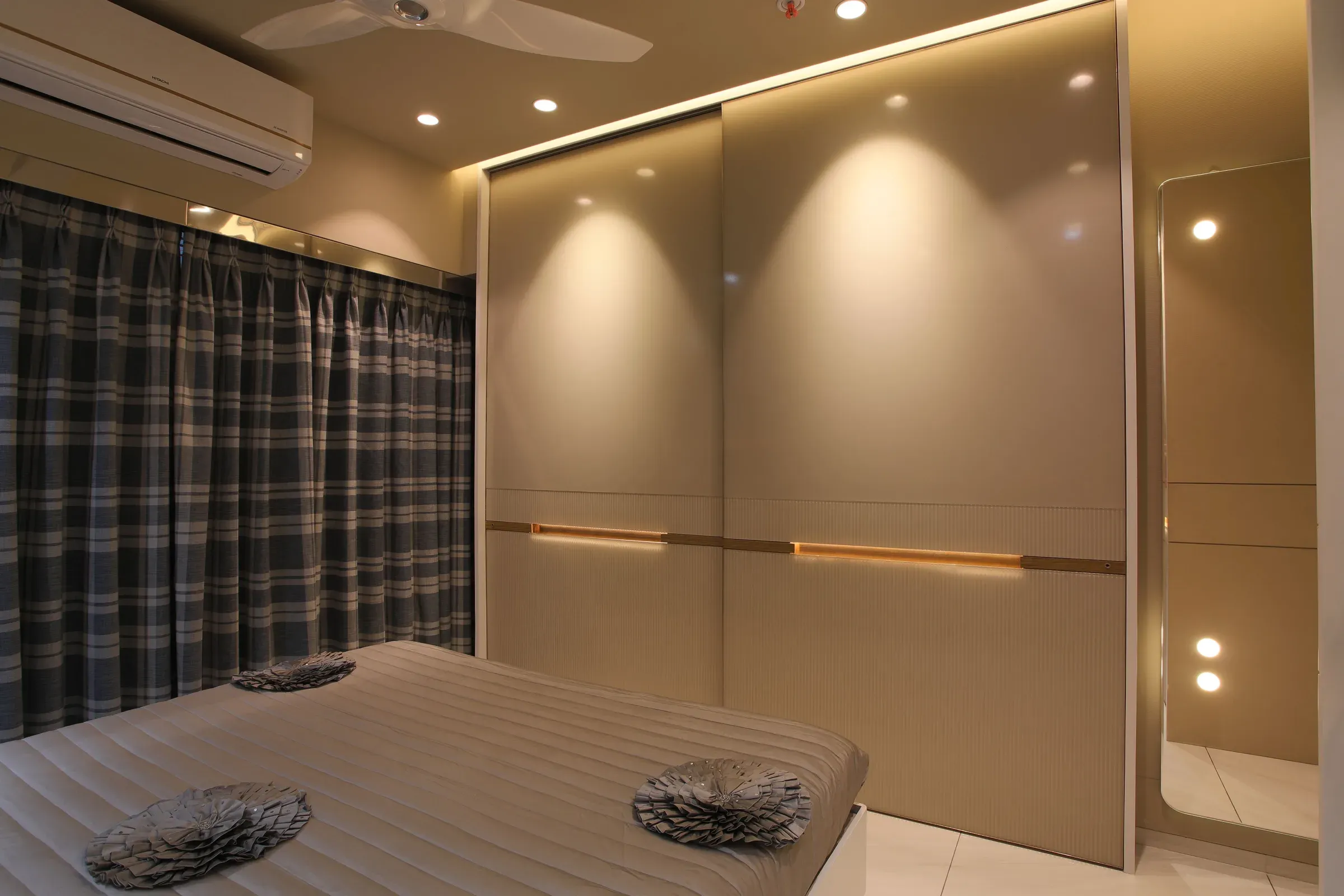 Bedroom with a beige gloss sliding wardrobe, LED handle strip, spotlights and checked curtains